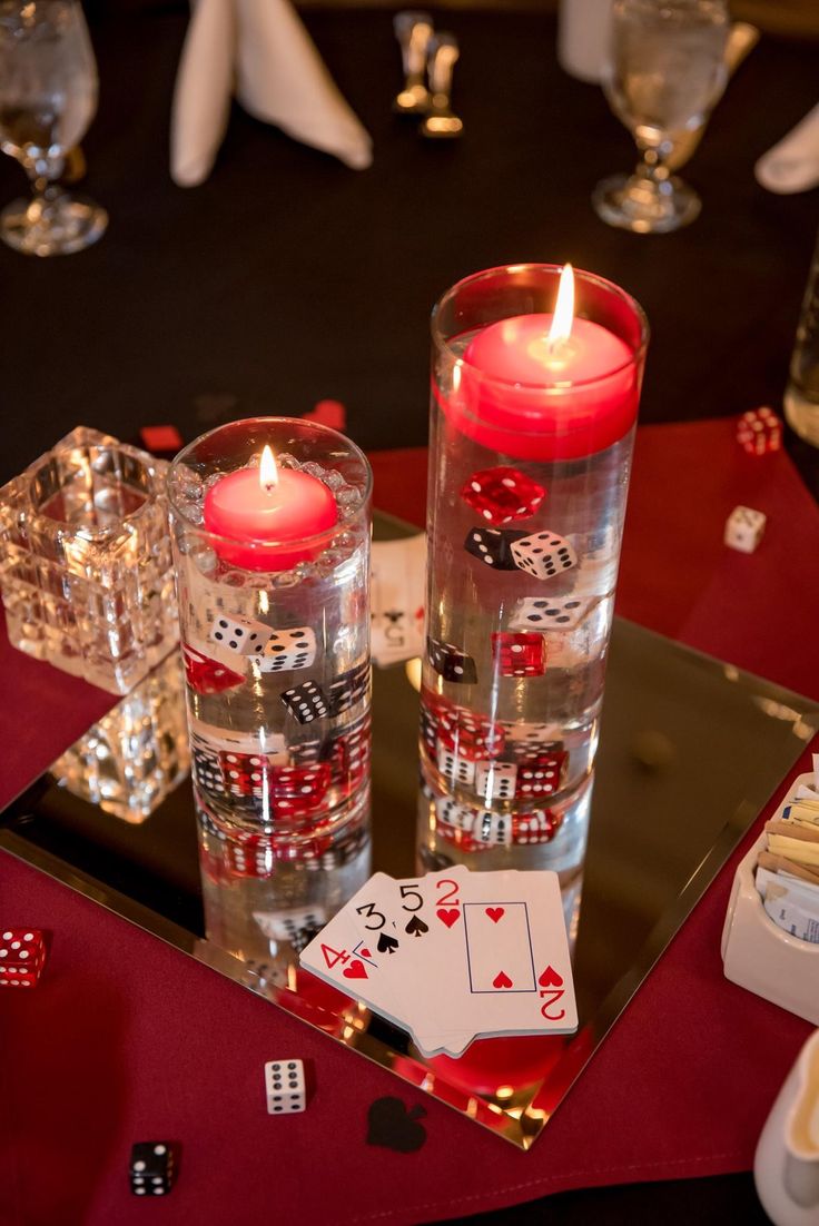 two candles sitting on top of a table with cards and dices in front of them