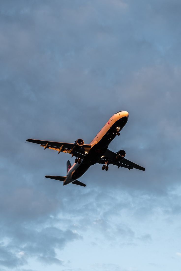 an airplane is flying in the sky on a cloudy day