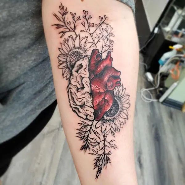 a heart tattoo on the arm with flowers and leaves around it, along with a sunflower