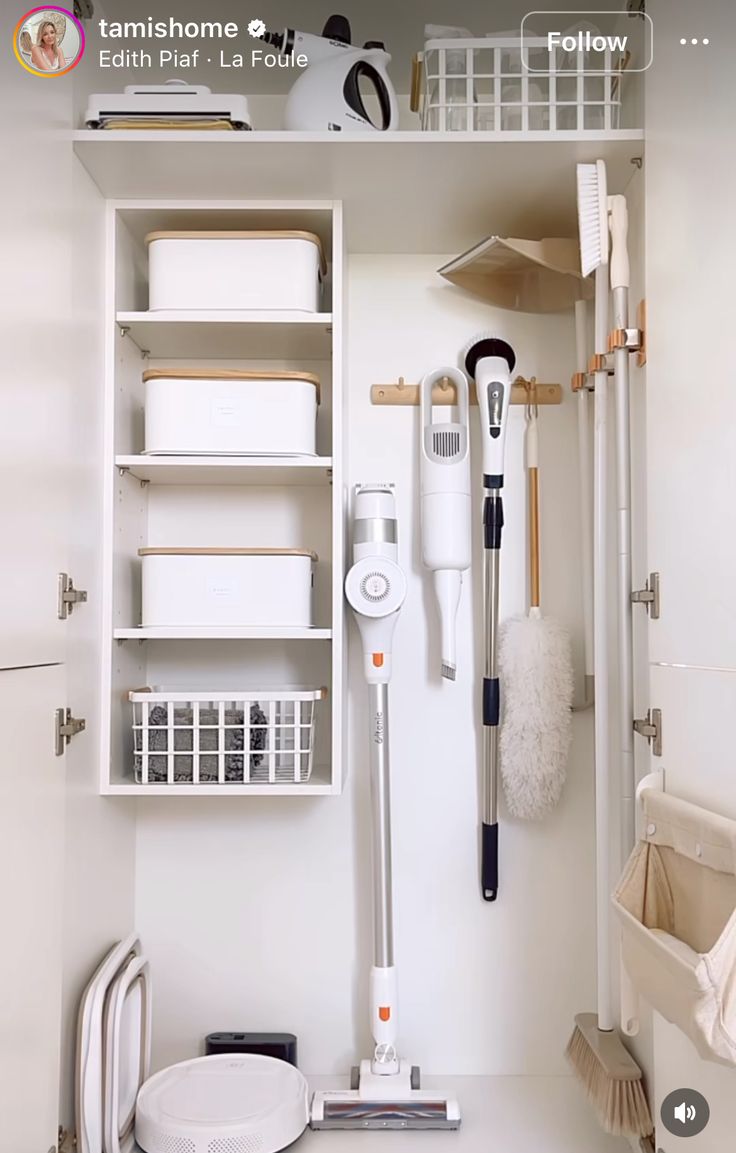 a white bathroom with lots of cleaning supplies on the shelf and in front of it