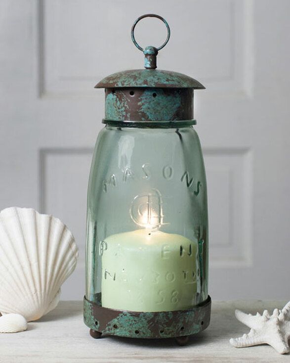 a glass jar with a candle inside sitting on a table next to seashells