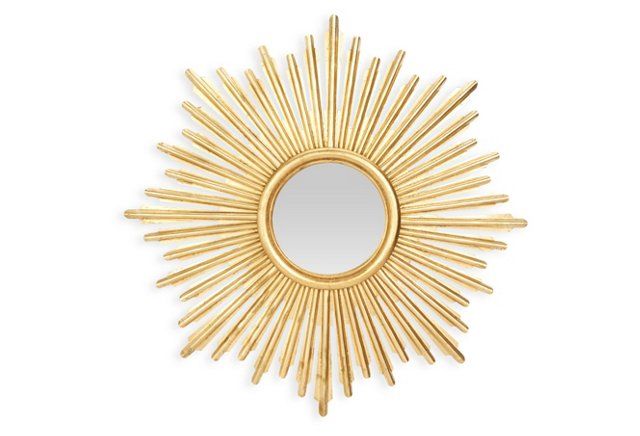 a gold sun mirror on a white wall