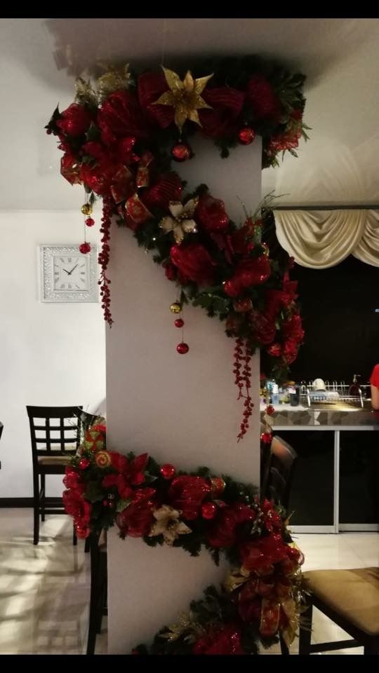 red flowers and greenery are growing up the side of a pillar in a living room