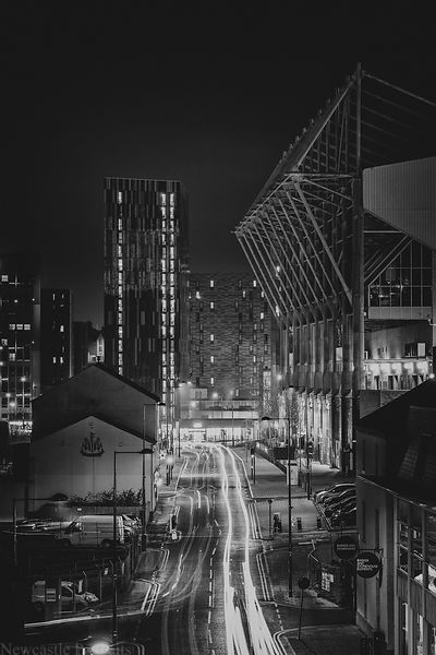 black and white photograph of city street at night with lights streaking down the road