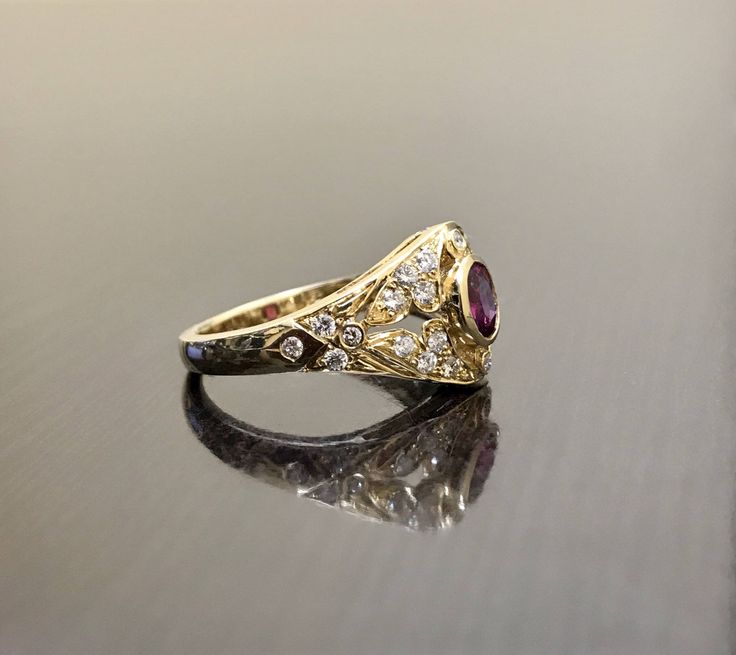 DeKara Designs Collection Metal- 18K Yellow Gold, .750. Stones- 1 Oval Ruby 0.50, 28 Round Diamonds G Color VS2 Clarity 0.22 Carats. Art Deco 18K Yellow Gold Ruby Diamond Engagement Ring. This ring features a beautiful reddish pink ruby that is half carat total weight, surrounded by 28 round diamonds. The center ruby is bezel set, 20 pave set diamonds, and 8 bezel set diamonds. The ring is entirely handmade, and could be hand engraved for an additional $200.00. The ring is a size 6 1/2, and coul Heirloom Gold Ruby Ring With Diamonds, Exquisite Yellow Gold Ruby Wedding Ring, Exquisite Yellow Gold Ruby Ring For Wedding, Heirloom Gold Ruby Ring With Center Stone, Yellow Gold Hallmarked Ruby Ring For Wedding, Hallmarked Yellow Gold Ruby Ring For Wedding, Luxury Gold Ruby Ring With Intricate Design, Formal Yellow Gold Ruby Ring With Single Cut Diamonds, Formal Gold Ruby Ring With Single Cut Diamonds