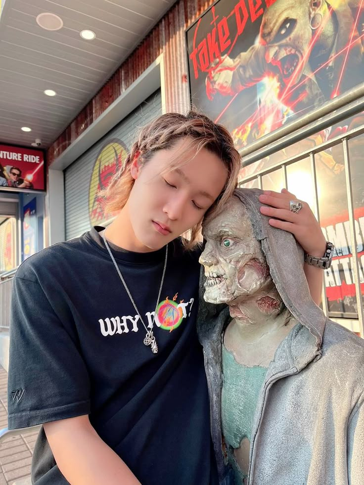 a young man standing next to a statue of a person with their head on the face