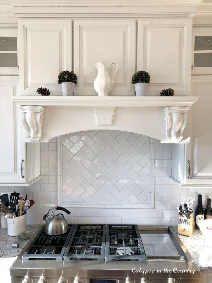 a stove top oven sitting inside of a kitchen next to white cabinets and counter tops