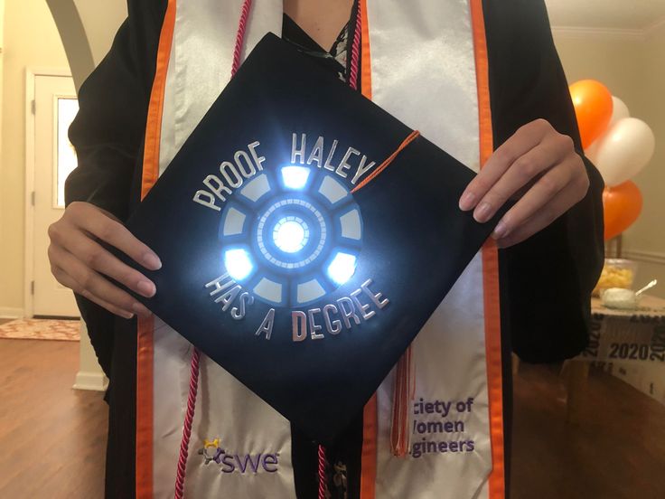 a person wearing a graduation cap and holding a light up square with the words proof halen has a degree on it