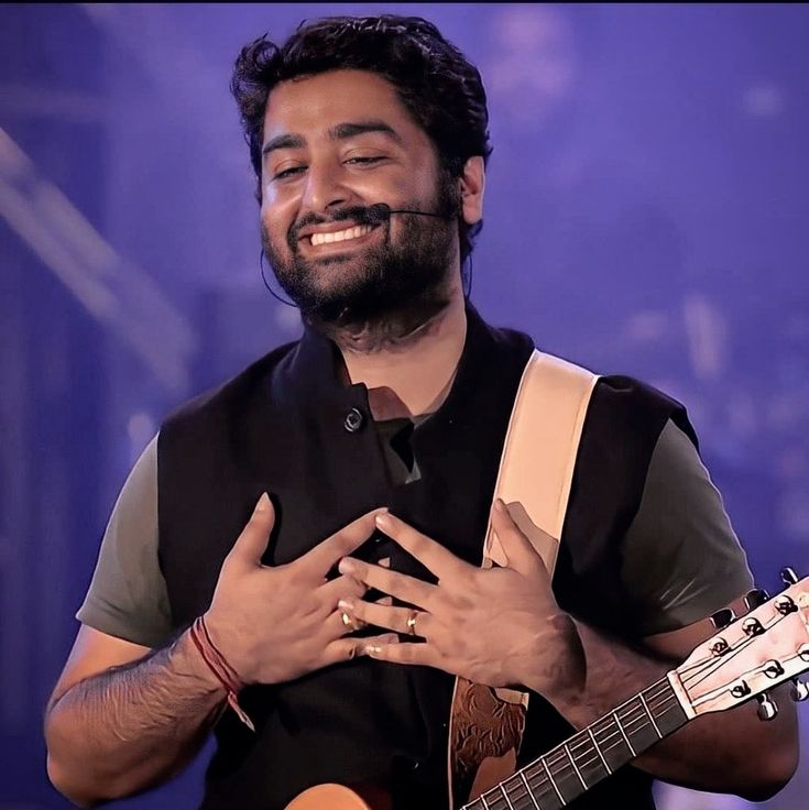 a man holding a guitar and smiling at the camera