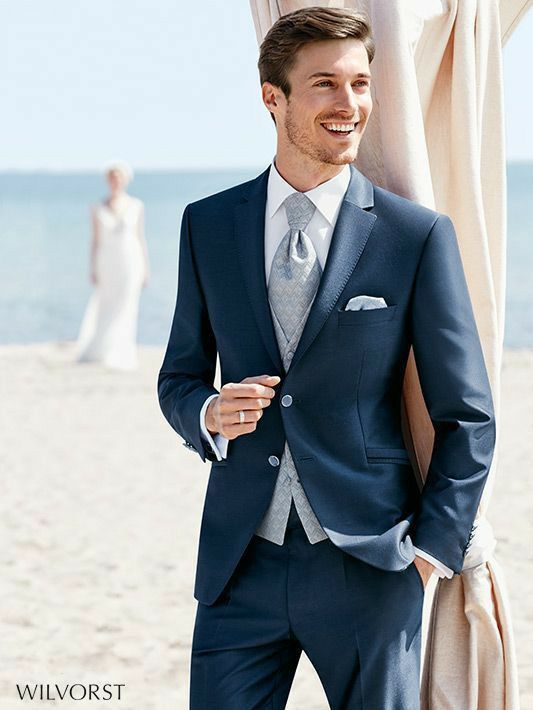 a man in a suit standing on the beach