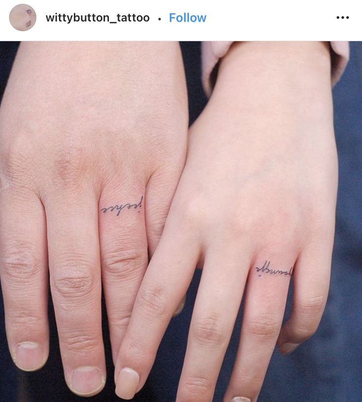 two hands with small tattoos on them, one is holding the other's hand