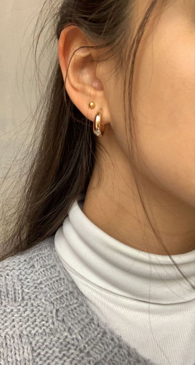 a close up of a person wearing some kind of gold earring on their left ear