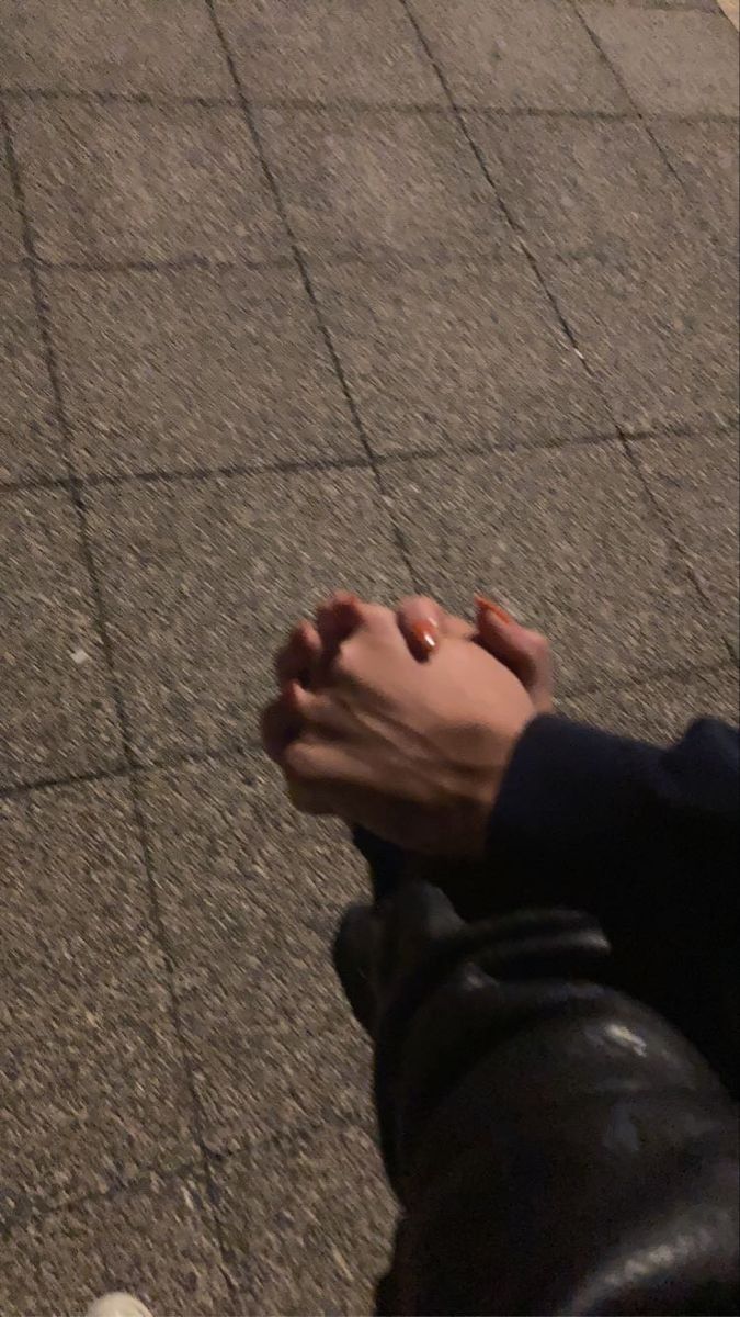 a person sitting on the ground holding their hand out to someone who is walking by