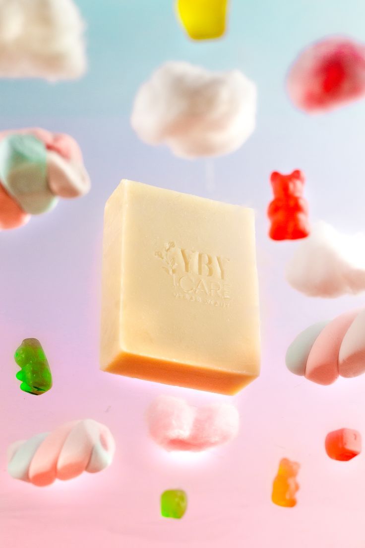 a soap bar floating in the air surrounded by gummy bears and candies on a pink background