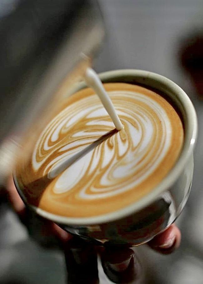 a person holding a cup of coffee with a spoon in it