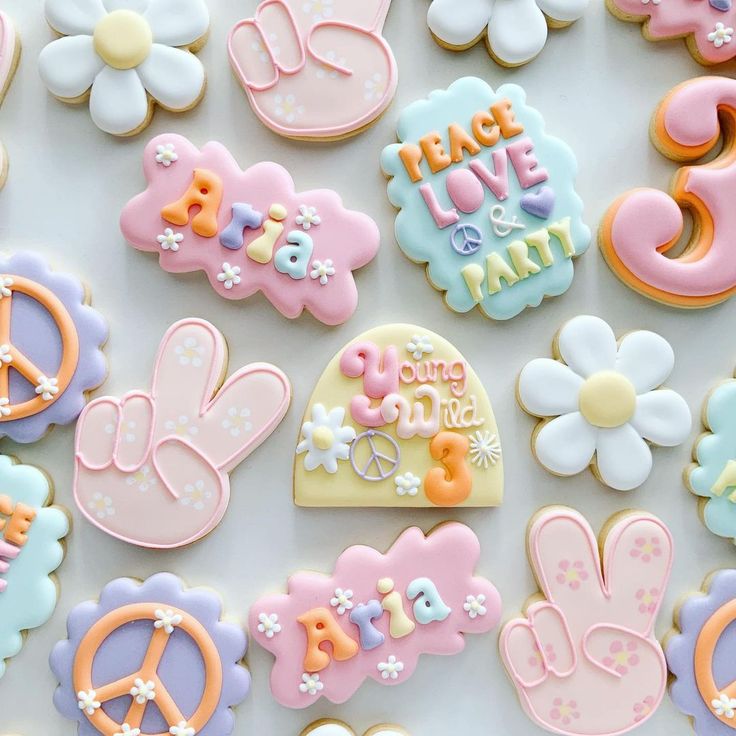 decorated cookies with peace, love, and birth symbols are displayed on a white surface