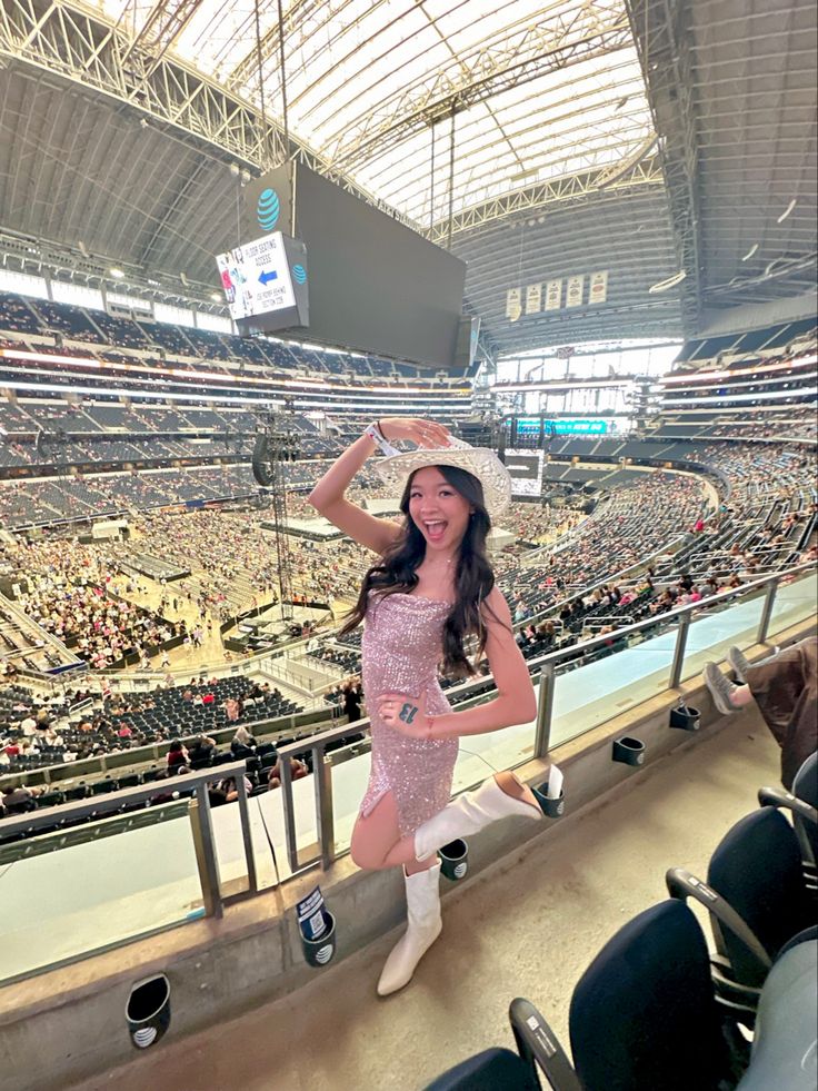 a woman in a pink dress and white cowboy hat at a baseball game, posing for the camera