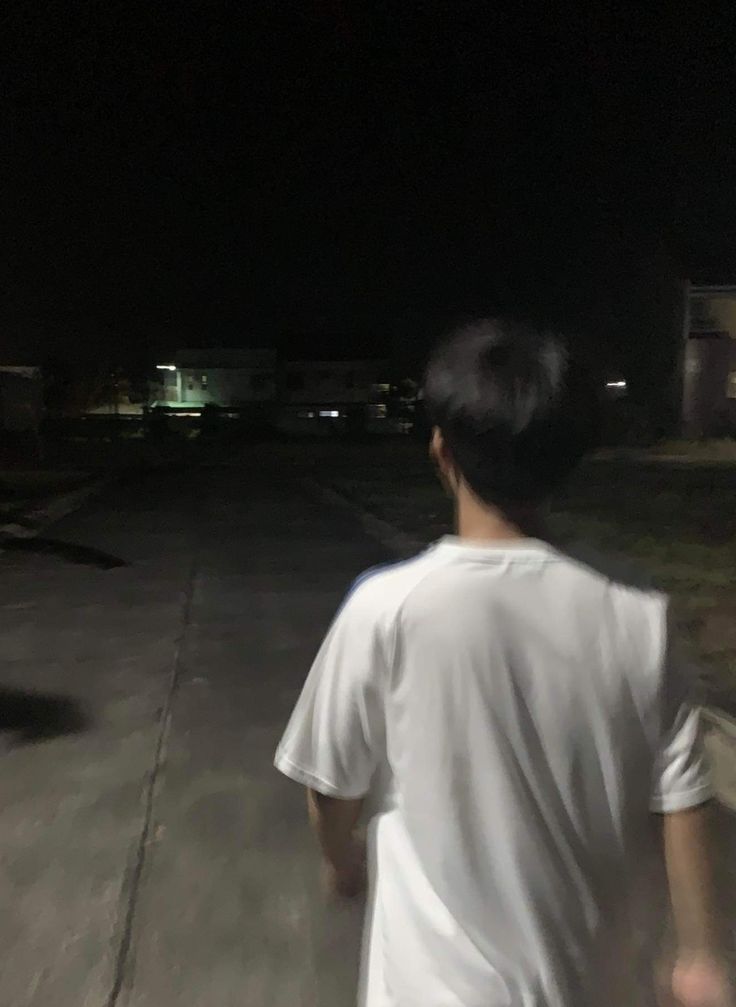 a young man is walking down the street at night