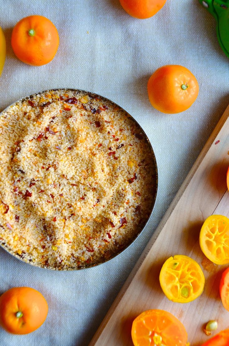 a bowl of food sitting on top of a wooden cutting board next to oranges