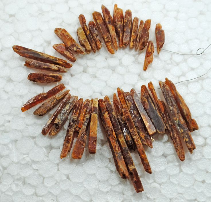 some brown and yellow beads are arranged in a circle on a white tablecloth with circles around them