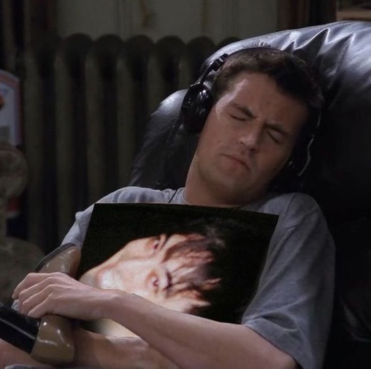 a man laying in a chair with headphones on and his face covered by a pillow