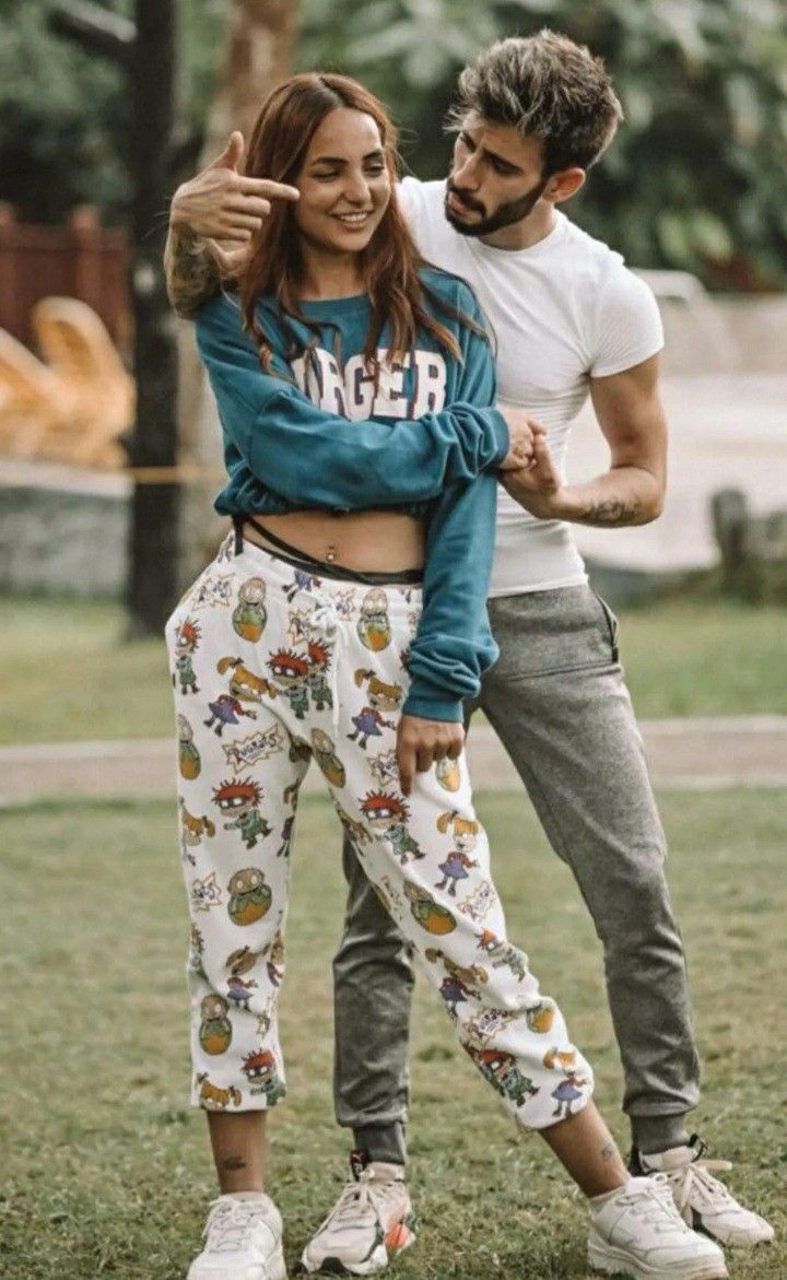 a man standing next to a woman on top of a lush green field