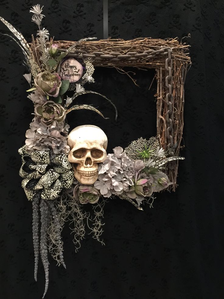 a wreath with a skull, flowers and branches in the shape of a square frame