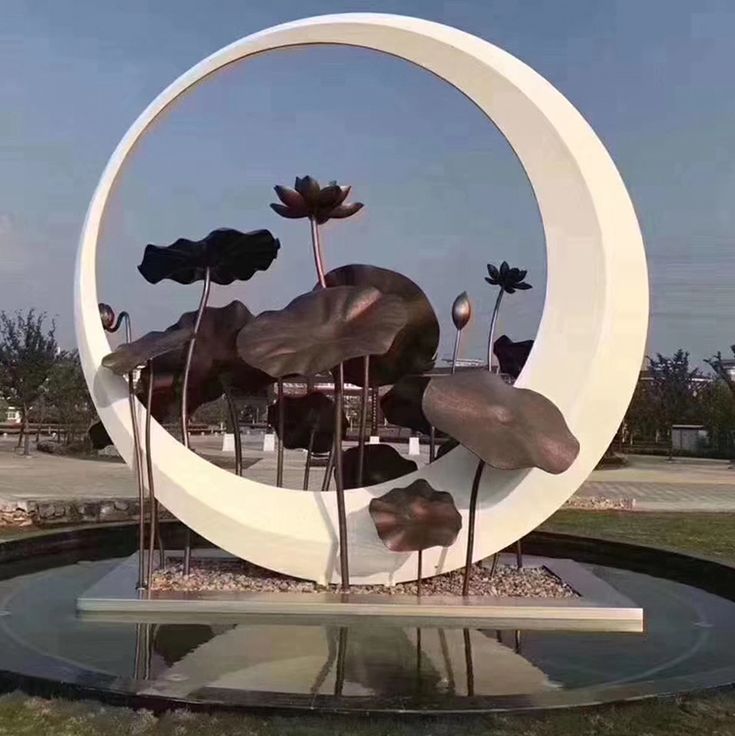 a sculpture is shown in the middle of a circular area with flowers growing out of it