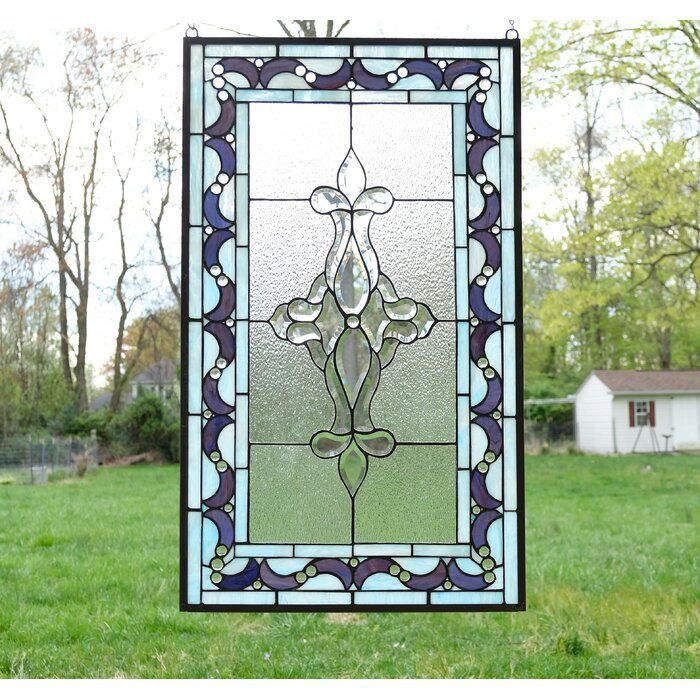 a stained glass window sitting on top of a lush green grass covered field in front of a house