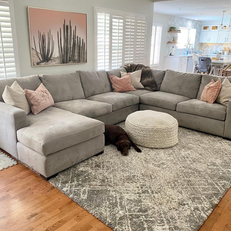 a living room with a large sectional couch and rug on the floor in front of it