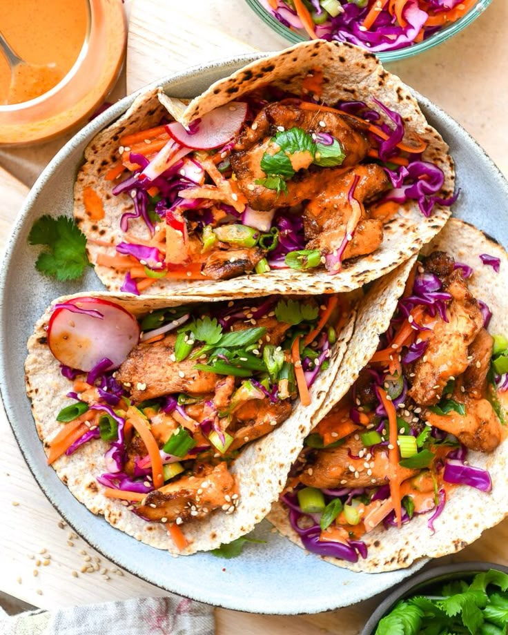 three chicken tacos on a plate with cole slaw