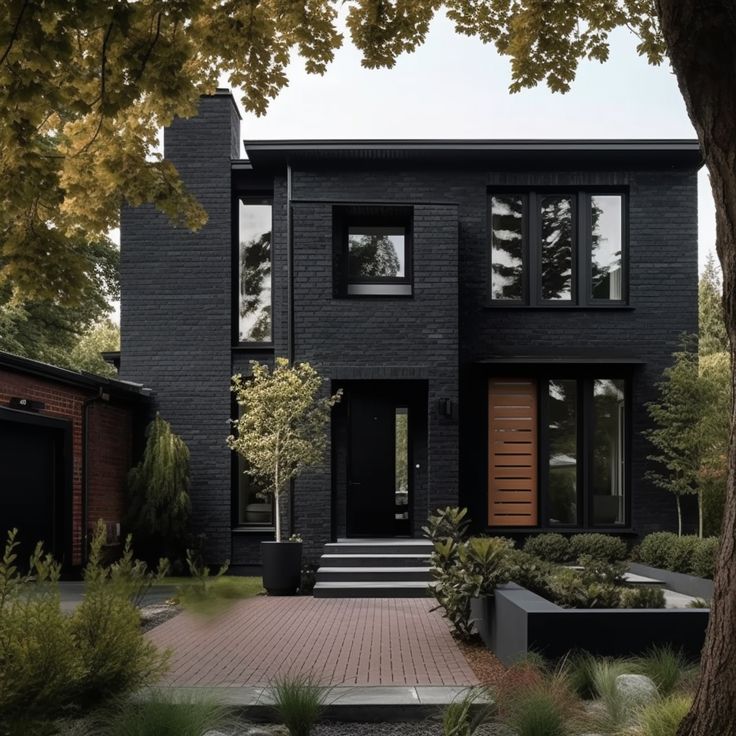 a large black house with lots of windows and plants in front of the entrance to it