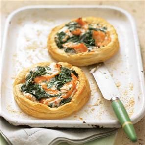 two small quiches with spinach and cheese on a baking sheet next to a knife