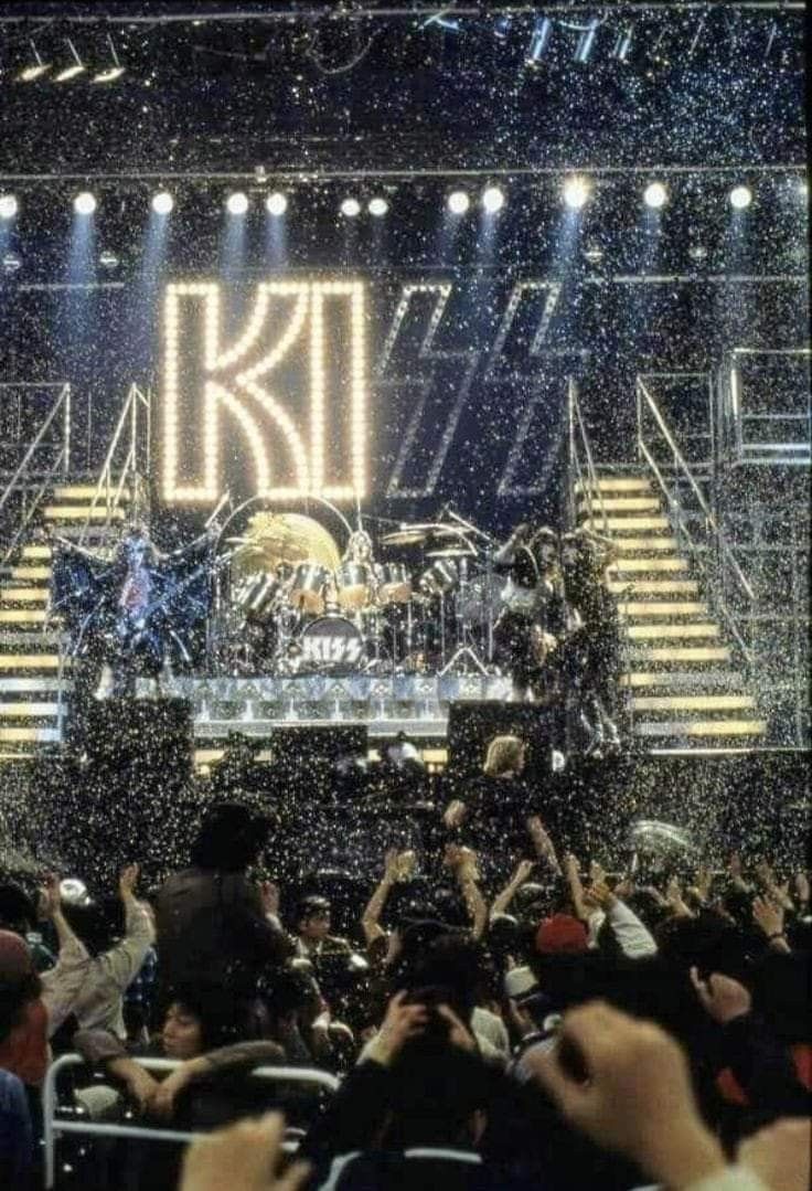 the band kiss performing on stage in front of an audience at a concert with lights and confetti