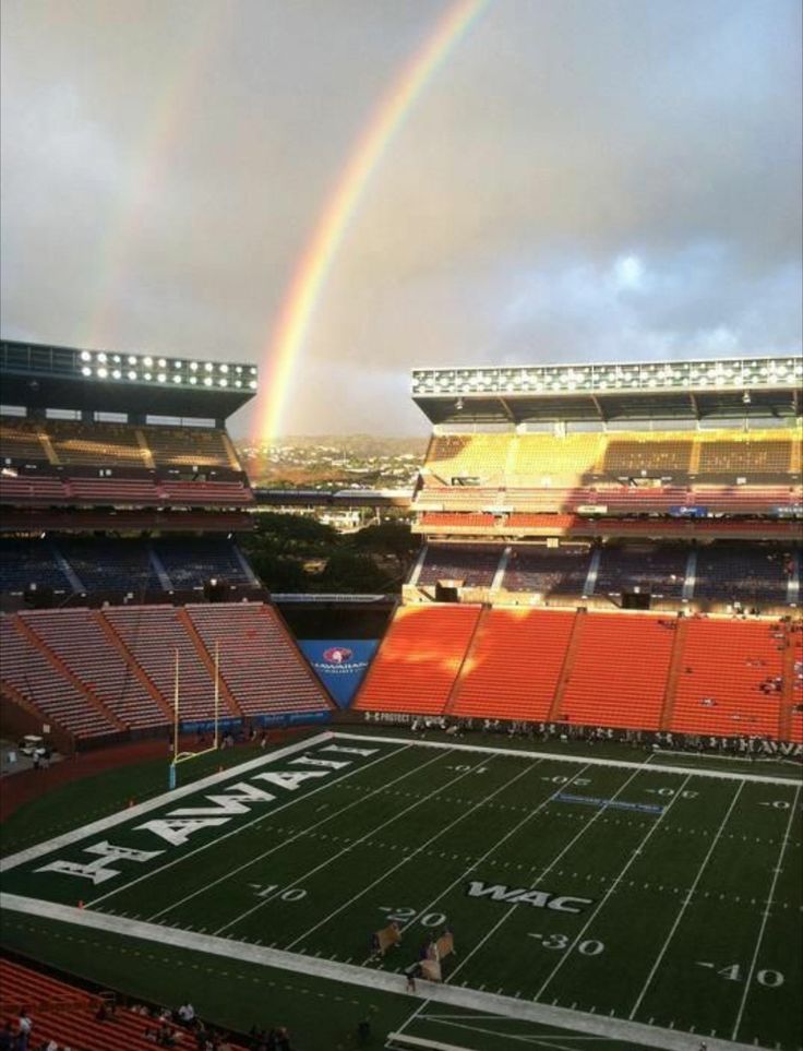 a rainbow shines in the sky over an empty football stadium