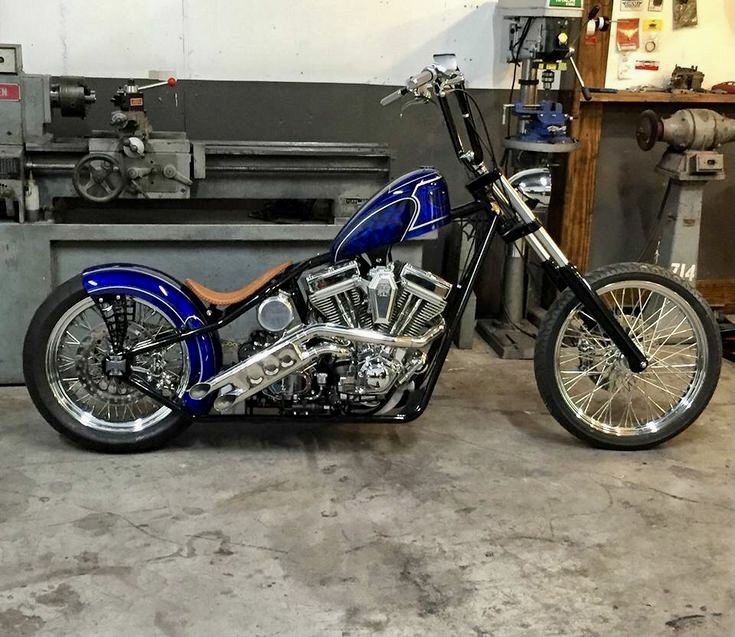 a blue motorcycle parked inside of a garage next to a machine tool box and other tools