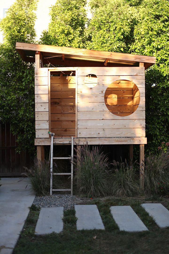 a small wooden outhouse in the middle of a yard with steps leading up to it