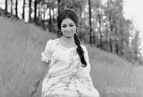 a woman in a white dress is walking through the grass with her long hair pulled back