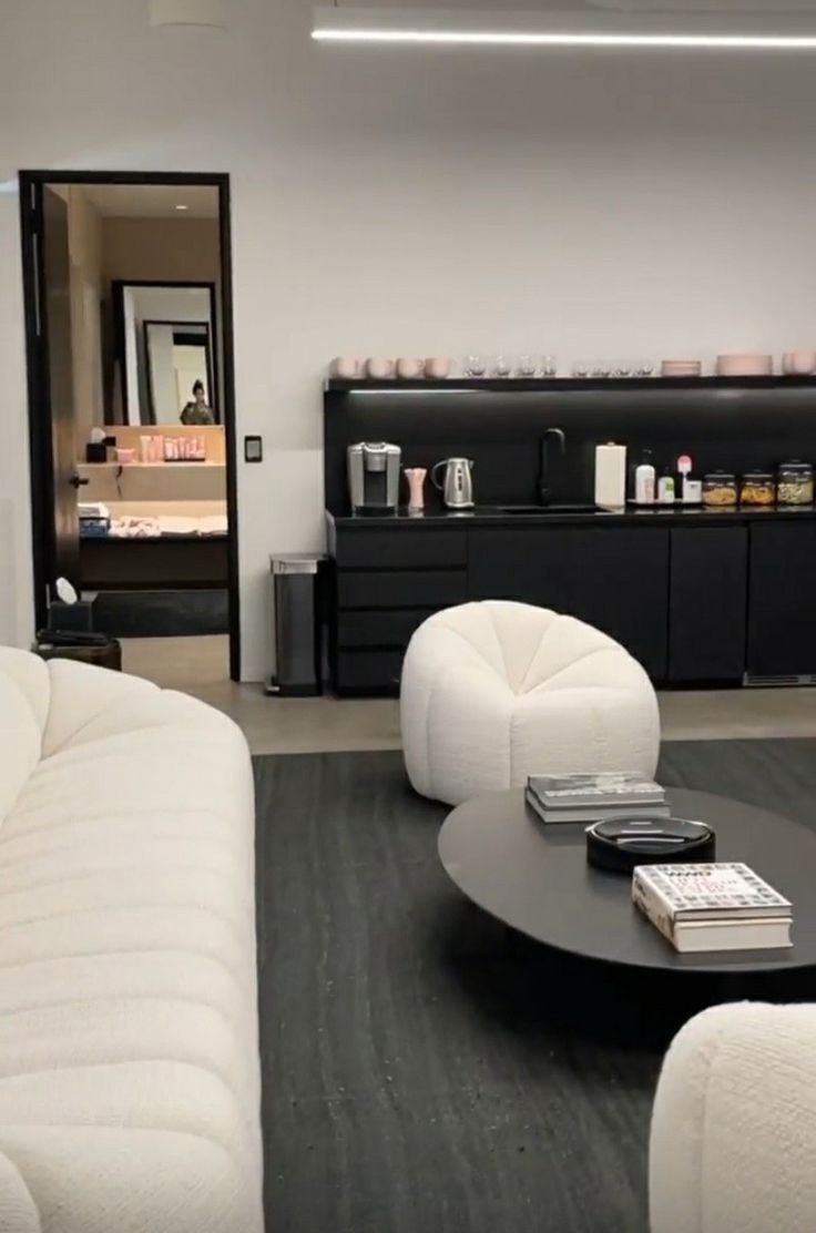 a living room filled with white furniture and a black coffee table in front of a mirror