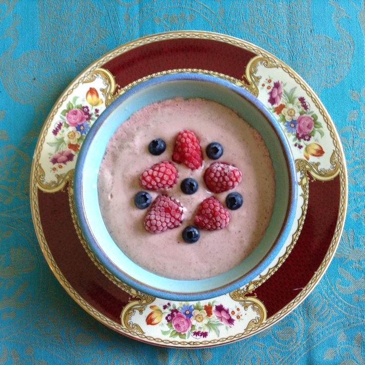 a bowl filled with berries and cream on top of a blue cloth covered tablecloth