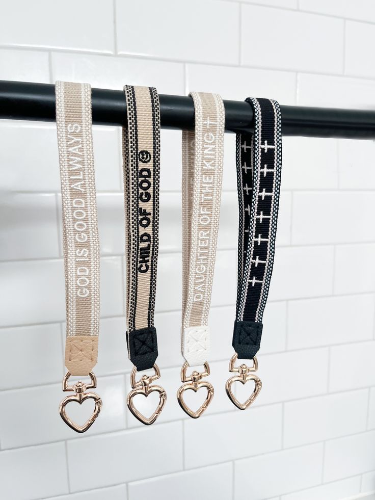 four lanyards hanging on a rail in a bathroom with white tile and black metal bars