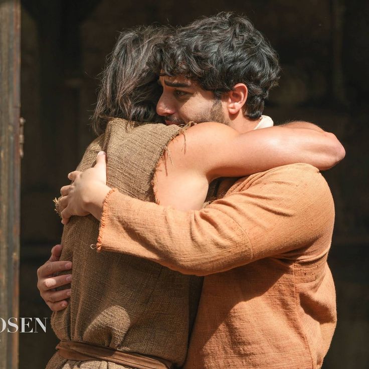 two people hugging each other in front of a building with an open doorway behind them