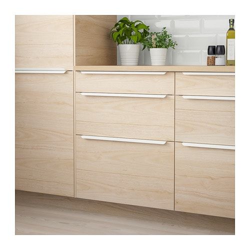 a kitchen with wooden cabinets and white counter tops, plants in pots on the top shelf