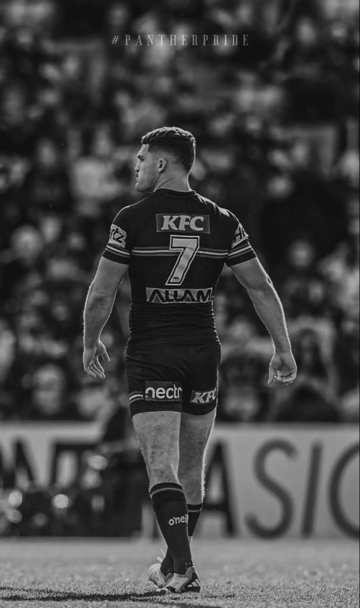 a rugby player is walking on the field in front of an arena full of people