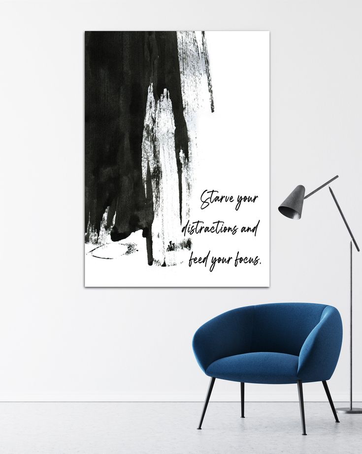 a blue chair in front of a white wall with a black and white painting on it