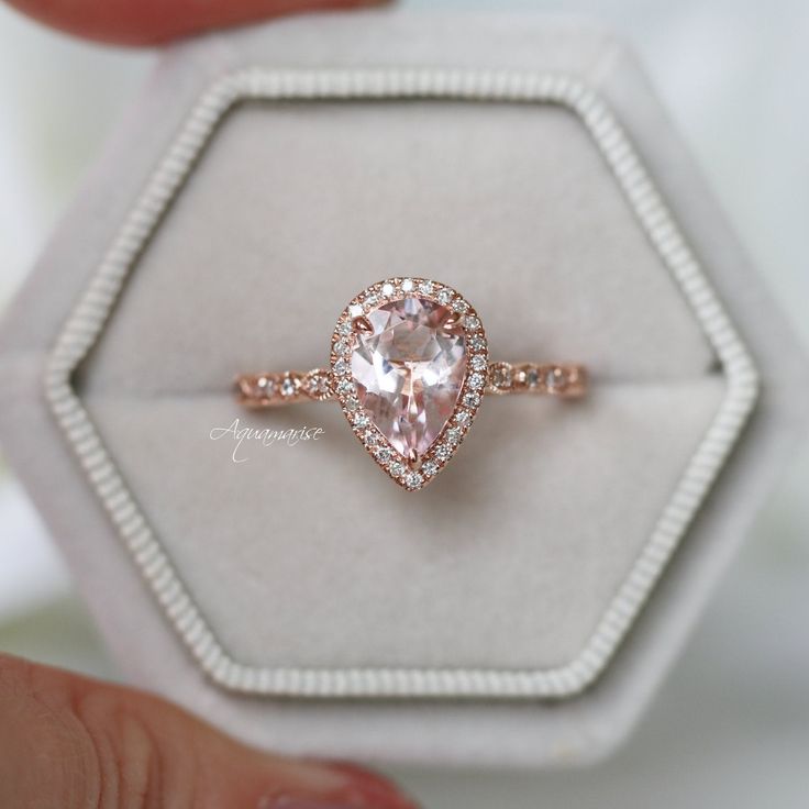 a close up of a ring with a pink diamond on it in a white box