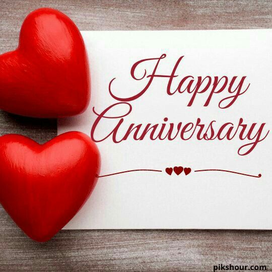 two red hearts sitting on top of a piece of paper with the words happy anniversary