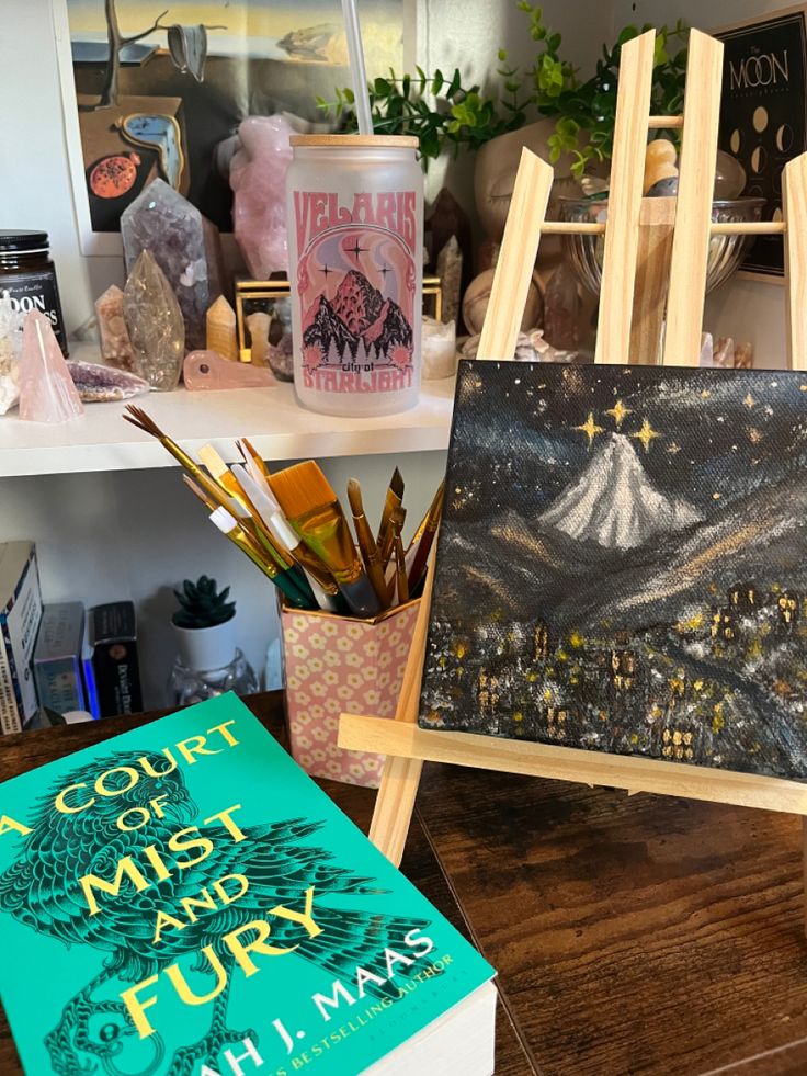 two books are sitting on a table next to some easels and paintbrushes