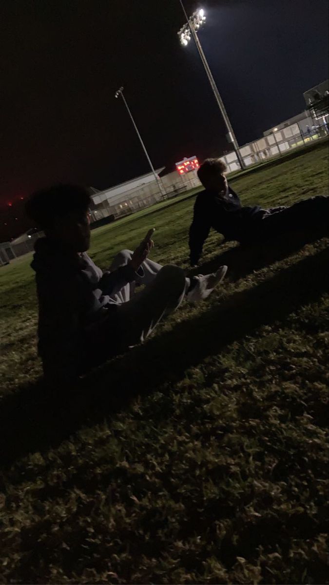 two people sitting in the grass at night