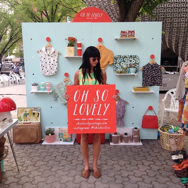 a woman holding a sign that says oh so lovely in front of an outdoor display